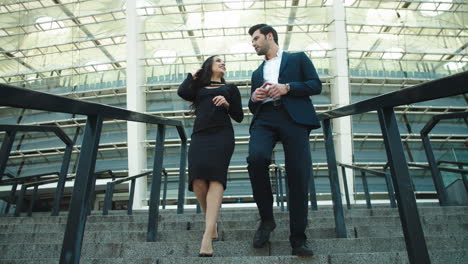 Two-business-partners-going-down-at-stairway-near-modern-building