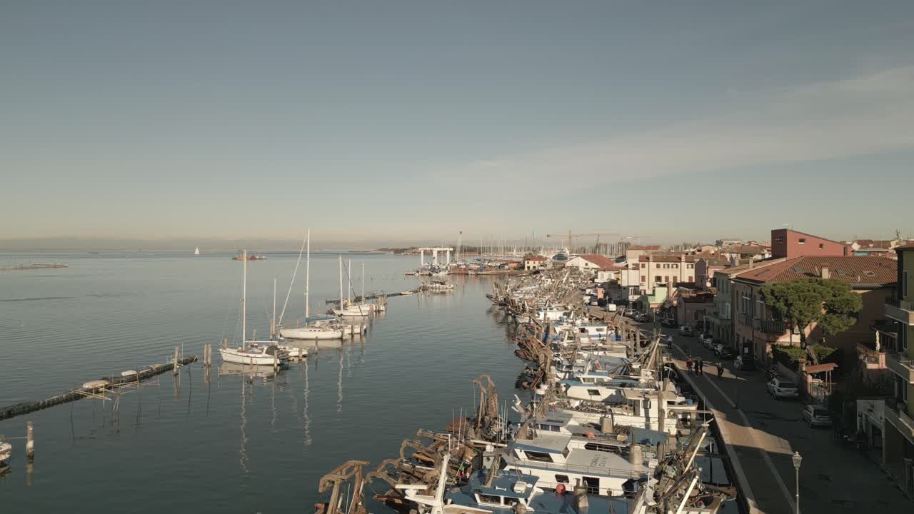 Ampia vista della marina di Chioggia con barche ormeggiate, bacino portuale e lungomare soleggiato
