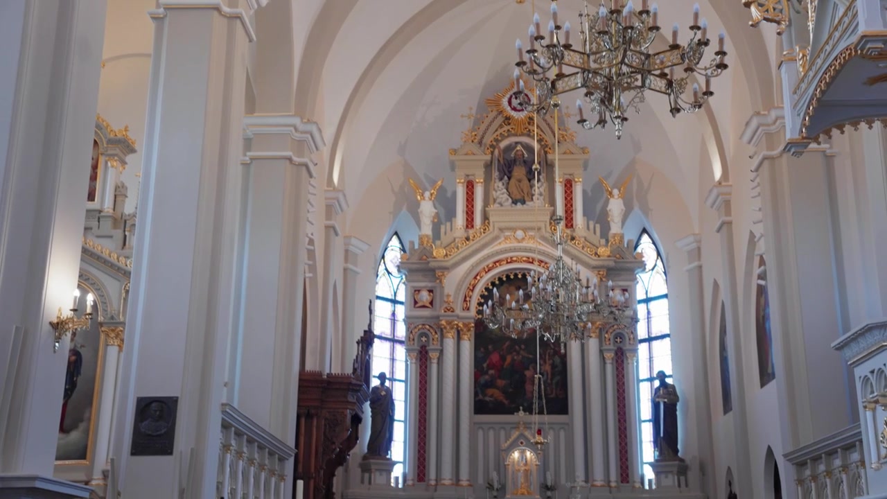 Splendide riprese grandangolari catturano l'interno di una cattedrale ornata con soffitti a volta, maestosi lampadari, un grande altare, luce diurna soffusa e dettagli classici. Nessuna persona, telecamera fissa.