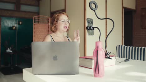 young bohemian woman speaking expressively by video call on her house terrace