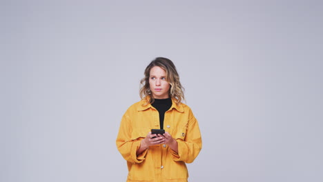 Studio-Shot-Of-Woman-Against-White-Background-Sending-Text-Message-On-Mobile-Phone-In-Slow-Motion