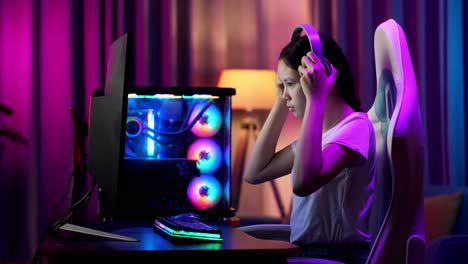 asian teen girl gamer wearing head phones and start play video game on computer