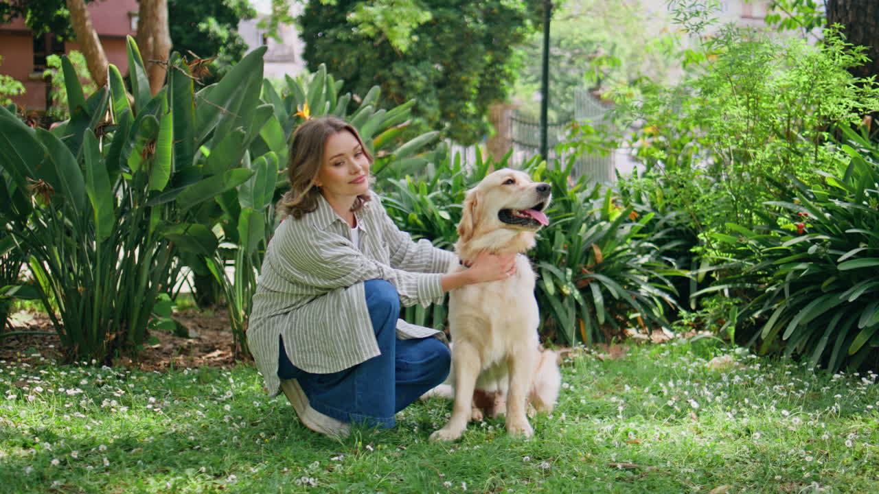 Young woman sitting retriever in green park closeup. Relaxed girl kneeling dog