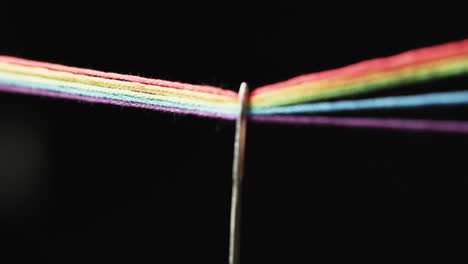 video de micro de hilos de color arco iris que pasan a través de la aguja con espacio de copia en fondo negro
