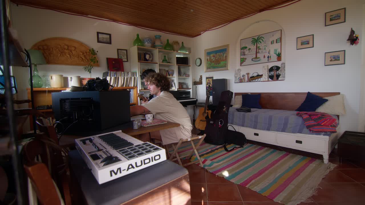 Friends collaborating in a music studio in Anacapri with guitar and keyboard, rear angle