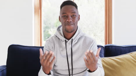 Happy-african-american-man-sitting-on-sofa-and-having-video-call-in-sunny-living-room,copy-space