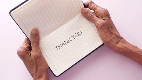 senior womens hand holding thank you note , top down