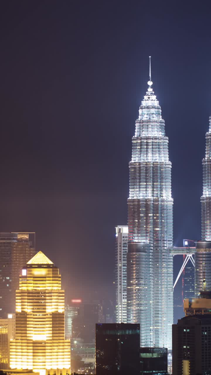 Panorámica en cámara rápida revela las Torres Gemelas Petronas en el horizonte nocturno de Kuala Lumpur