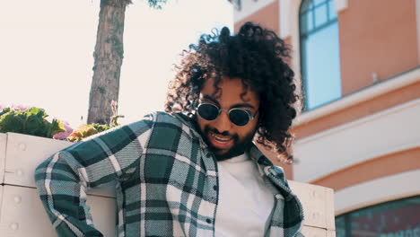 man with curly hair and sunglasses in an urban setting