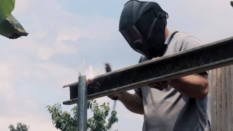 professional welder employing industrial welding machine to put together two pieces of metal creating a metalic structure as part of his daily work at a local small business