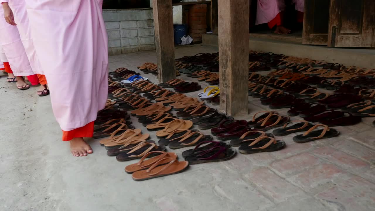 las monjas budistas se quitan las sandalias en filas ordenadas antes de entrar en el comedor de un monasterio fuera de mandalay, myanmar.