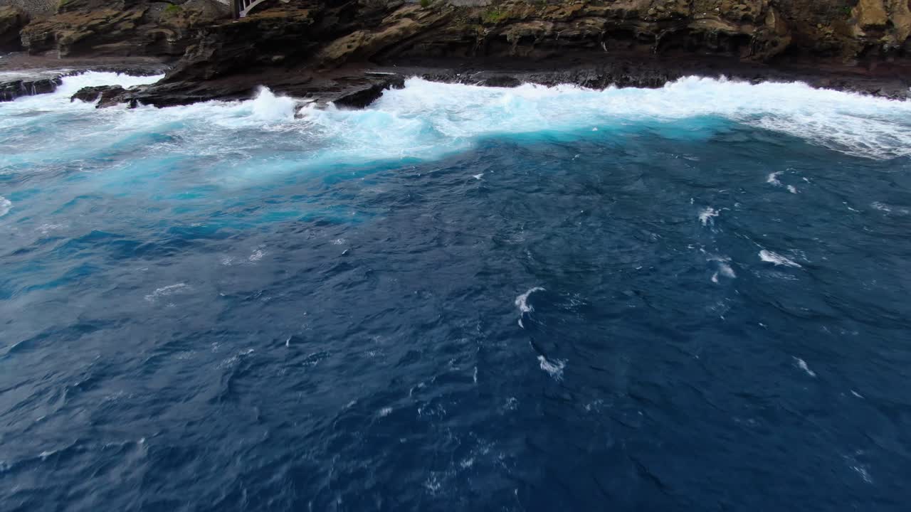 drone volando lejos de los acantilados marinos mientras se inclina hacia arriba para revelar la carretera hawaiana