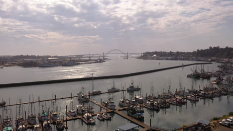 newport oregon, drone above boats moored in harbor, silhouette of yakina bay bridge in distance