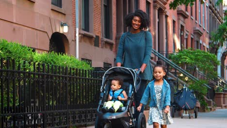 mother pushing buggy with two daughters in the street