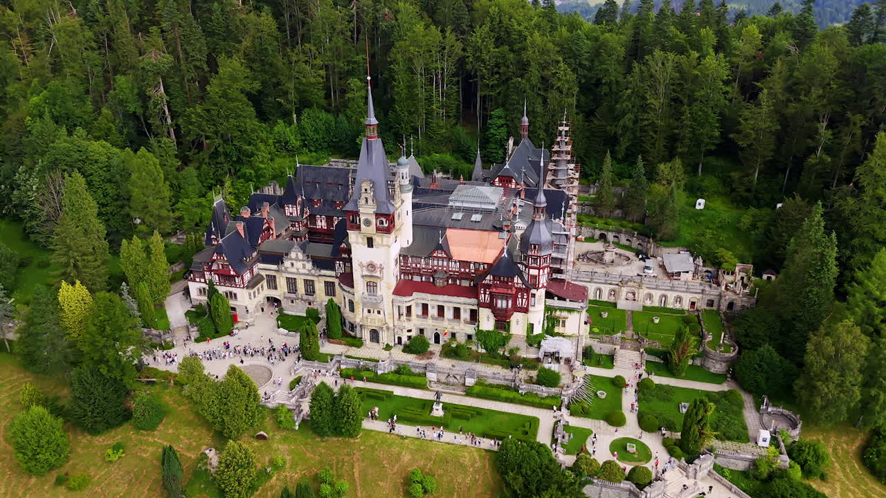 Monet ihmiset kävelevät Peleșin linnan ympäristössä, Prahovan piirikunnassa, Romaniassa. Lähestymme upeaa arkkitehtuuria drone-näkökulmasta.