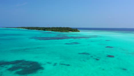 quiet tropical island with lush vegetation and palm trees in the middle of indian ocean, surrounded by calm lagoon with coral reef on seabed