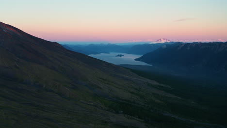 Aerial-dolly-shot-of-a-sunset-landscape-over-a-rural-mountain-horizon,-pink-and-purple-sky