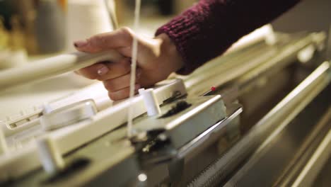 female hands making knitted texture on weaving machine