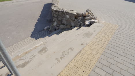 collapsed stone wall in city next concrete slabs, poorly maintained infrastructure, medium handheld pan