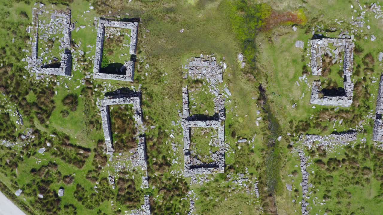 Deserted village ruins walls at slievemore, achill island, ireland, aerial top down. close up to wide and drone ascends.