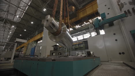 large metal part being lifted and positioned on a machine in a factory