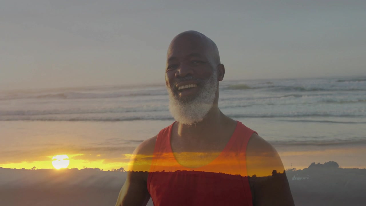 Uomo anziano che si ferma a riflettere girandosi sulla spiaggia, con una fascia di luce calda che gli attraversa il busto, sorridendo in un momento di vita sereno