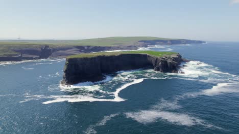 aerial view of illaunonearaun islet with kilkee cliffs and wind turbines in the background