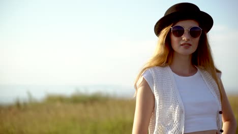 woman in field with hat and sunglasses