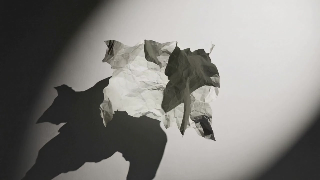 Shifting spotlight casting changing shadows on plain white backdrop, revealing crumpled sheet folds
