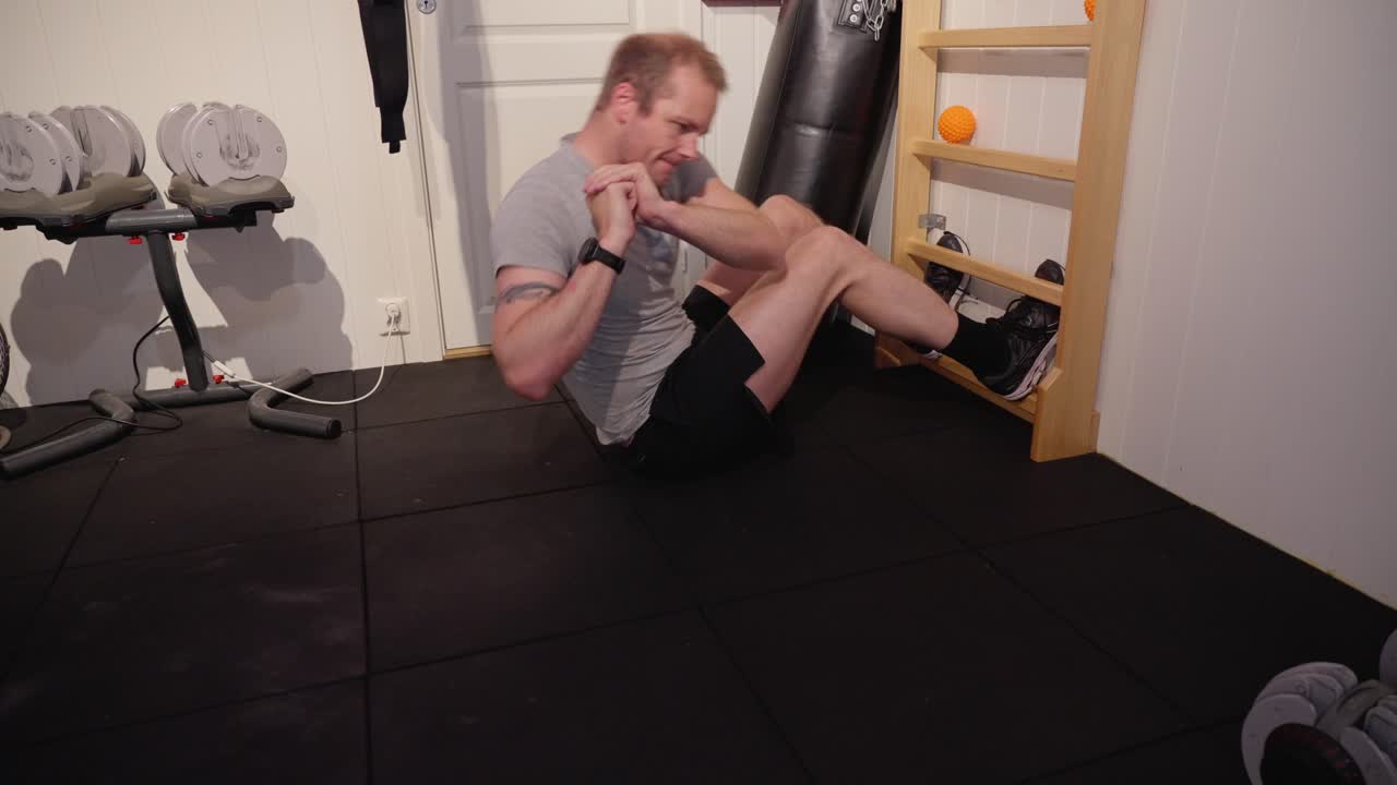 Person performs twisting sit ups on rib wall, focusing on core and oblique muscles during a home workout