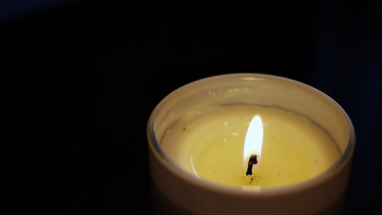 Blikající svíčka s tmavým pozadím.