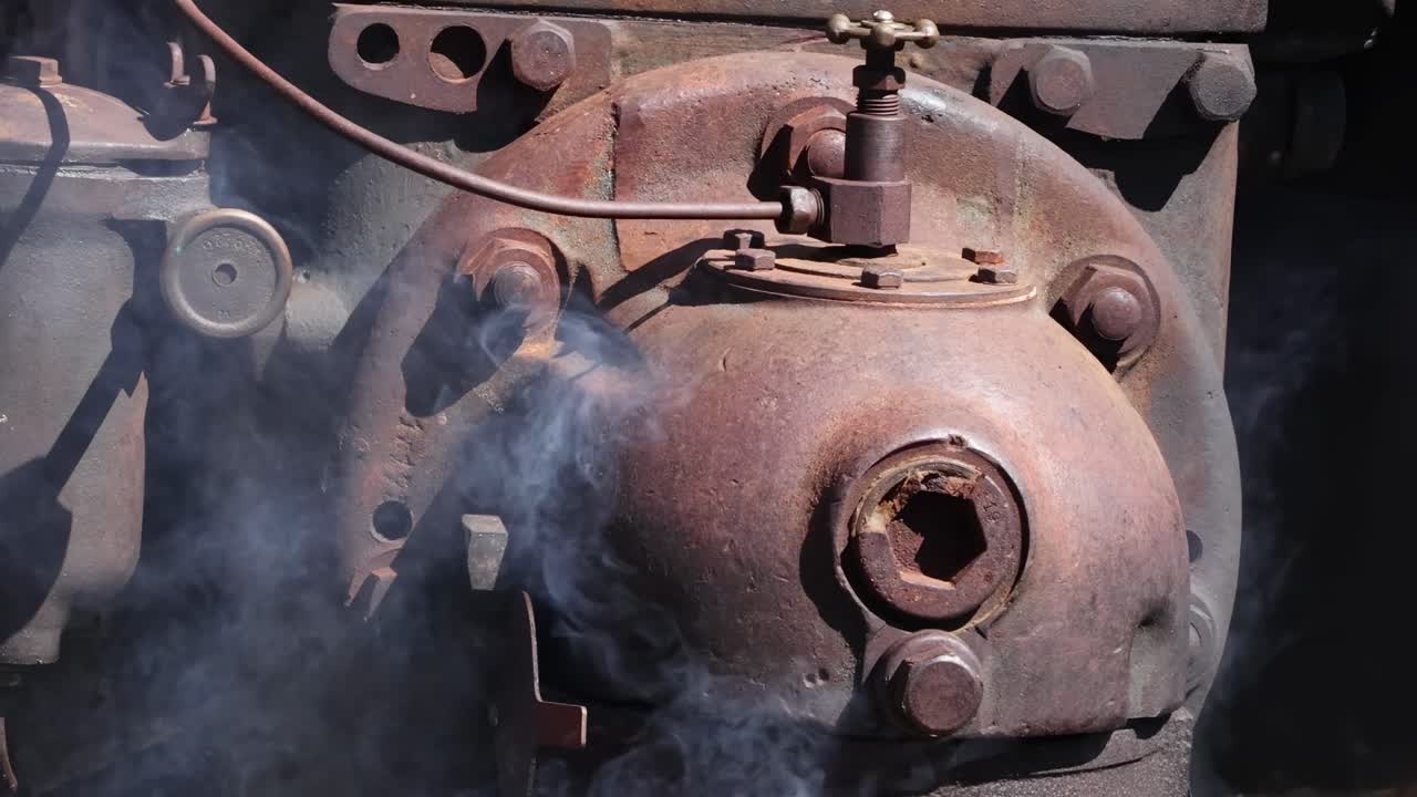 Detailed view of a steam engine part with smoke emission and visible mechanical features.