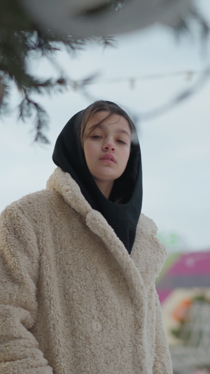 후드 코트를 입고 매달린 장식과 줄 조명을 올려다보는 백인 십 대, 클로즈업 인물 사진, 겨울 숨결, 도시 스카이라인 블러, 주머니에 손을 넣고 반사하는 듯한 포즈, 축제 장식, 부드러운 느낌