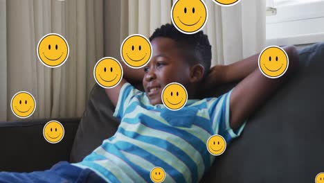 Animation-of-emoji-icons-over-happy-african-american-boy-lying