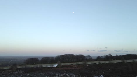un dron de 4k disparó volando sobre campos congelados hacia una luna llena justo después del atardecer