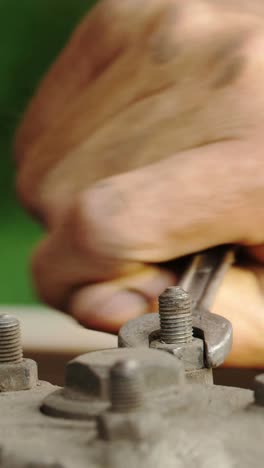 close-up of hand using wrench to fix bolts