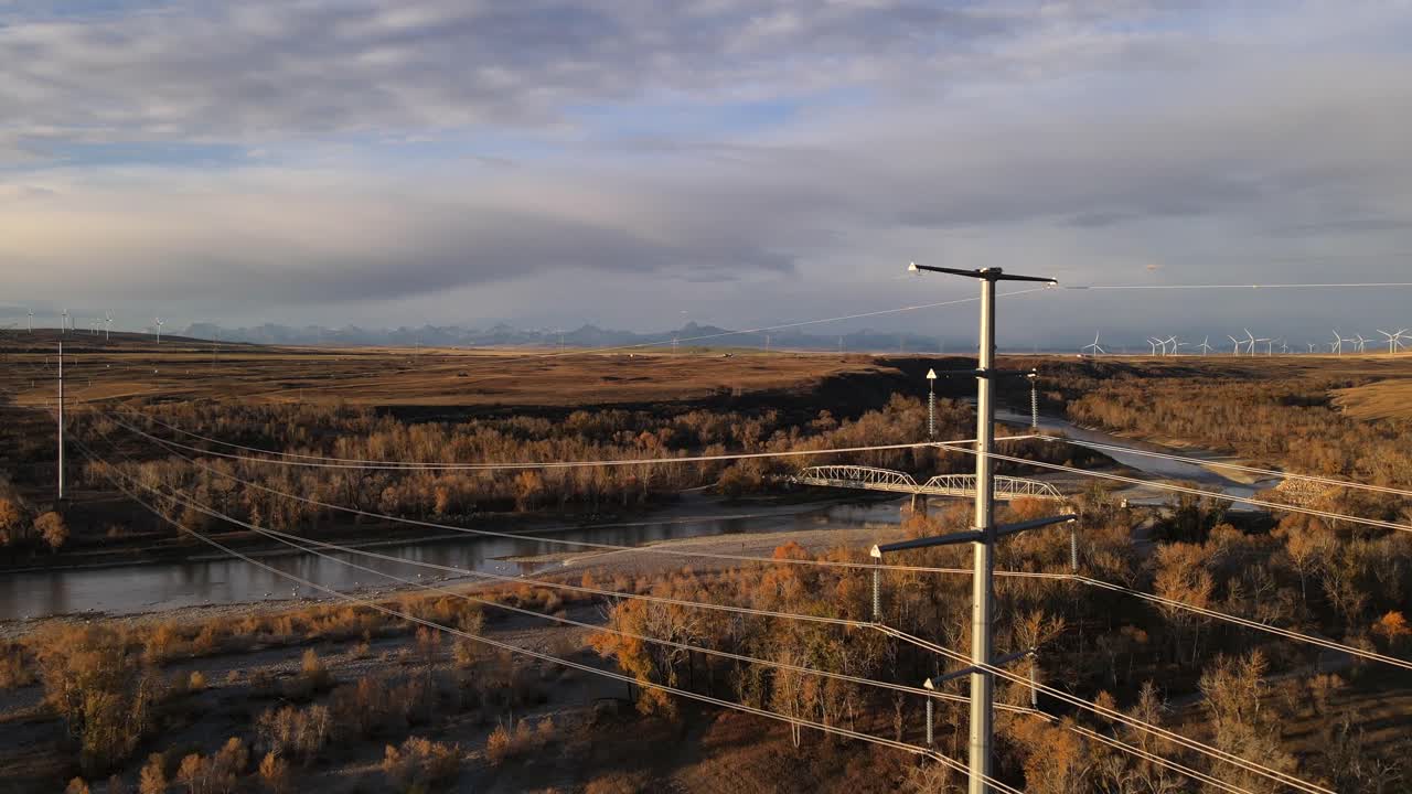 Drone flying backwards through power lines in southern Alberta, Canada. Close call with electricity poles. Cinematic aerial footage of beautiful old bridge in the outskirts of the Rocky Mountains.
