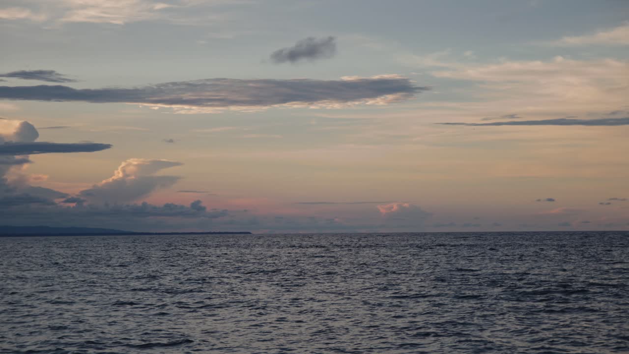 Aerial pan left over Cocles beach at midday, showcasing turquoise waters and lush green rainforest under clear skies.