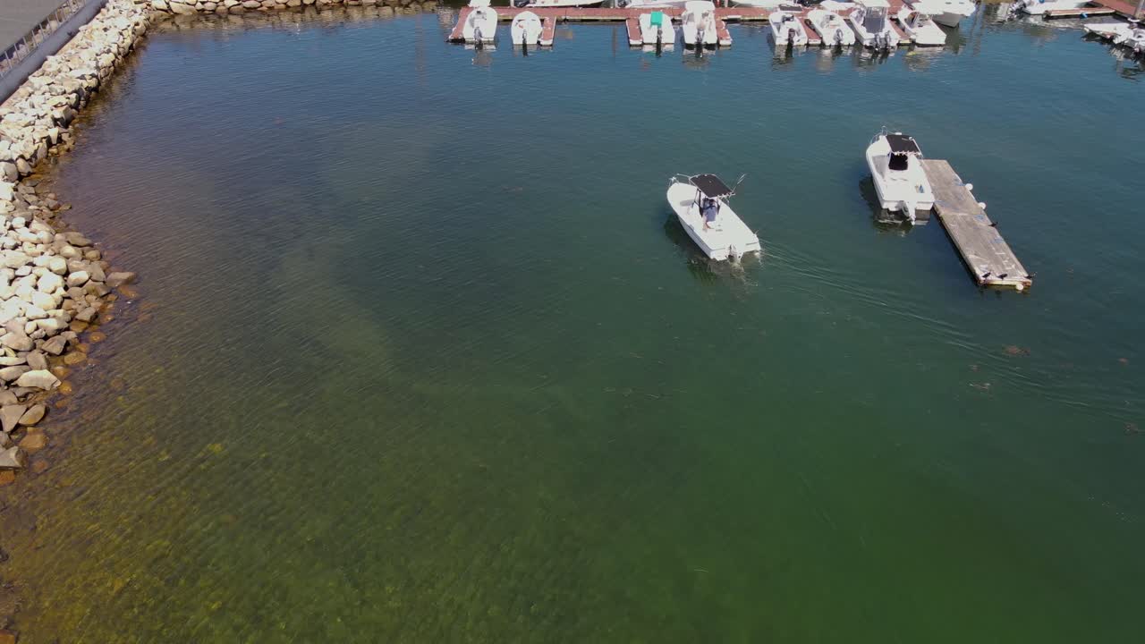 Luftoptagelse af en lille motorbåd, der positionerer og fortøjer til jetski
