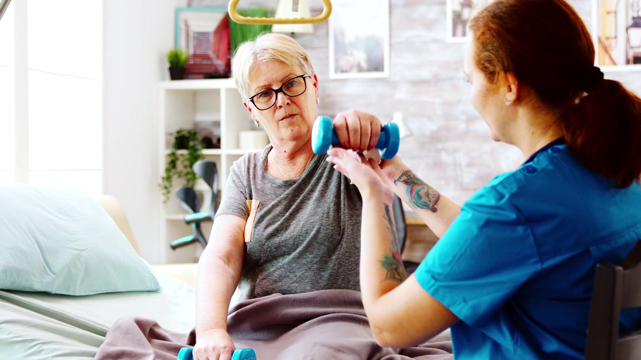Physiotherapeutin unterstützt Seniorin bei Hantelübungen