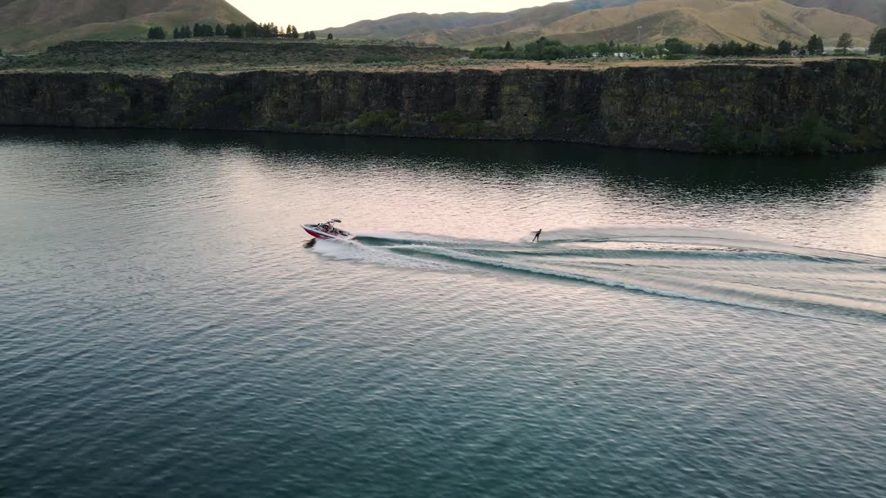 Side view of a girl wakeboarding at sunset on the lake.