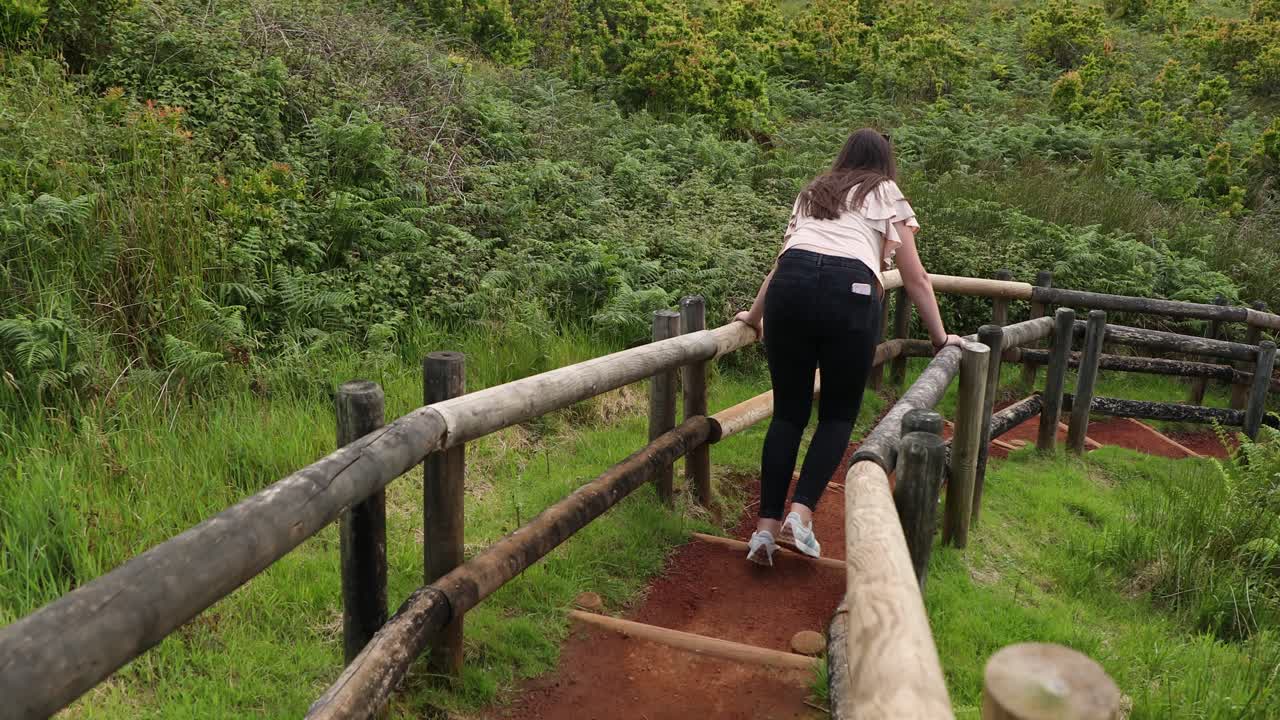 vista detrás de una mujer bajando las escaleras en furnas do enxofre en la isla de terceira, portugal