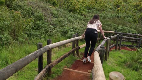 View-Behind-A-Woman-Walking-Down-The-Stairs-At-Furnas-do-Enxofre-In-Terceira-Island,-Portugal