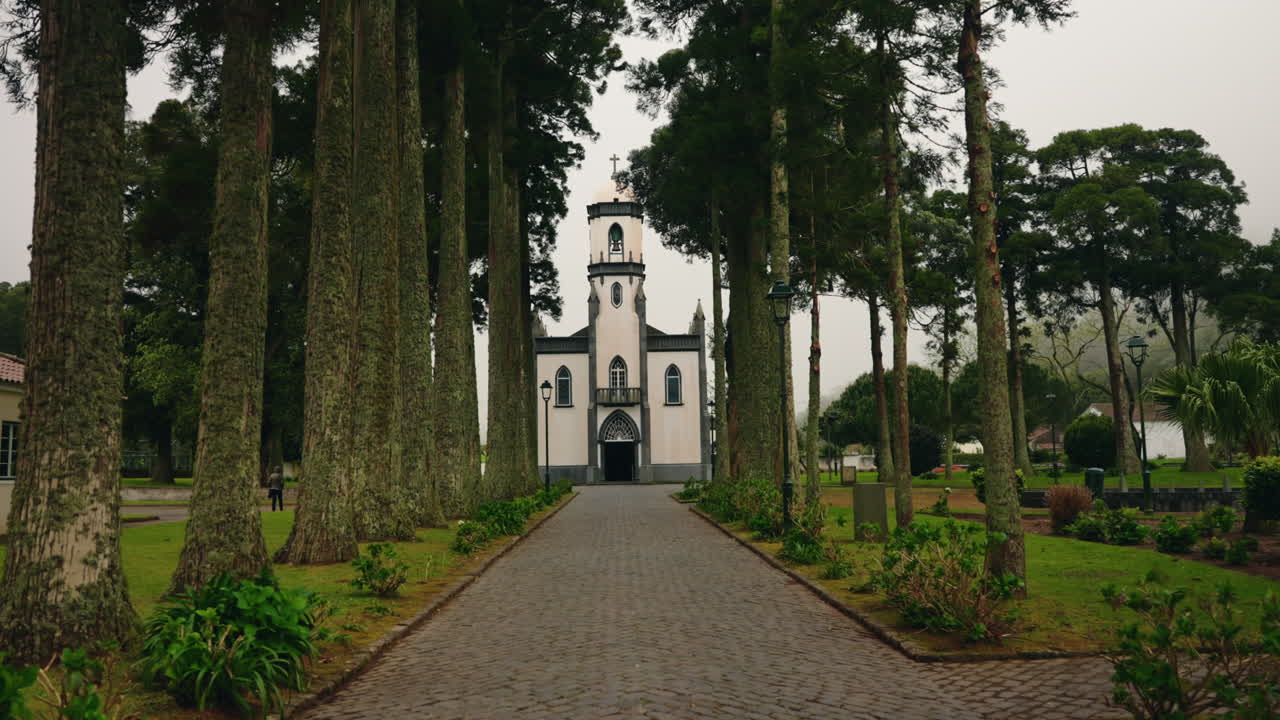 caminando por el camino hacia la vista frontal de la fachada de la pequeña iglesia local ubicada en la isla de sao miguel, azores