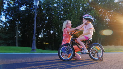 mother wears a crash helmet daughter who sits on a children's bicycle concept - the protection and c