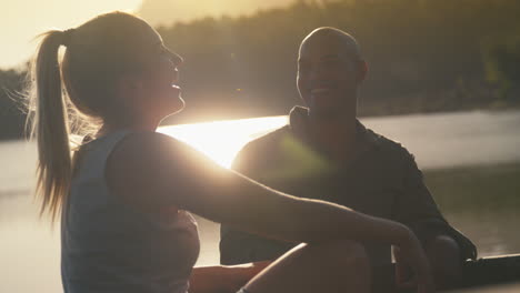 couple sitting in back of pick up truck on road trip by lake at sunset