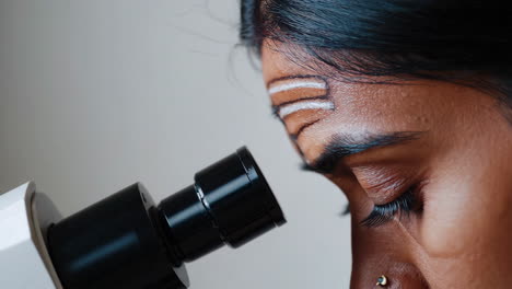 close-up of a scientist observing through a microscope