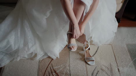 bride adjusting her wedding shoes, with her dress spread out around her, sitting on a carpet