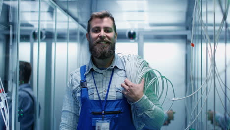 it technician smiling in a data center holding cables