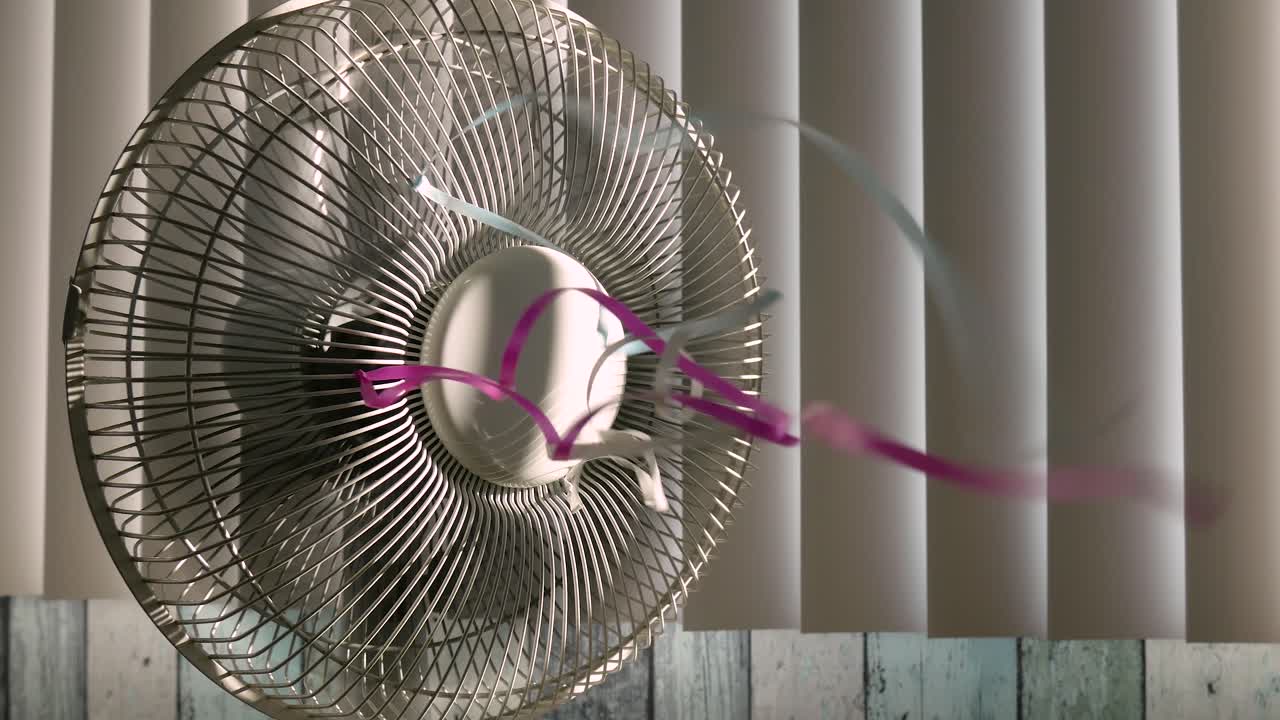 그릴에 화려한 리본이 달린 회전하는 팬의 왼쪽에서 오른쪽으로 트럭이 햇빛을 비추는 닫힌 창 블라인드를 배경으로 촬영했습니다.